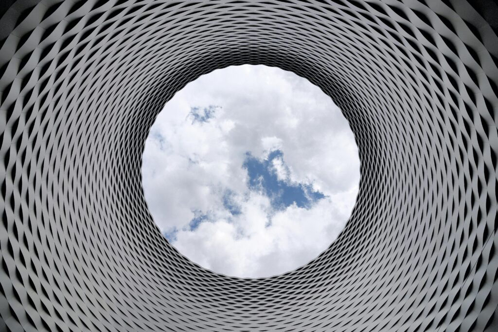 Modern architectural tunnel with a geometric pattern revealing a bright sky.